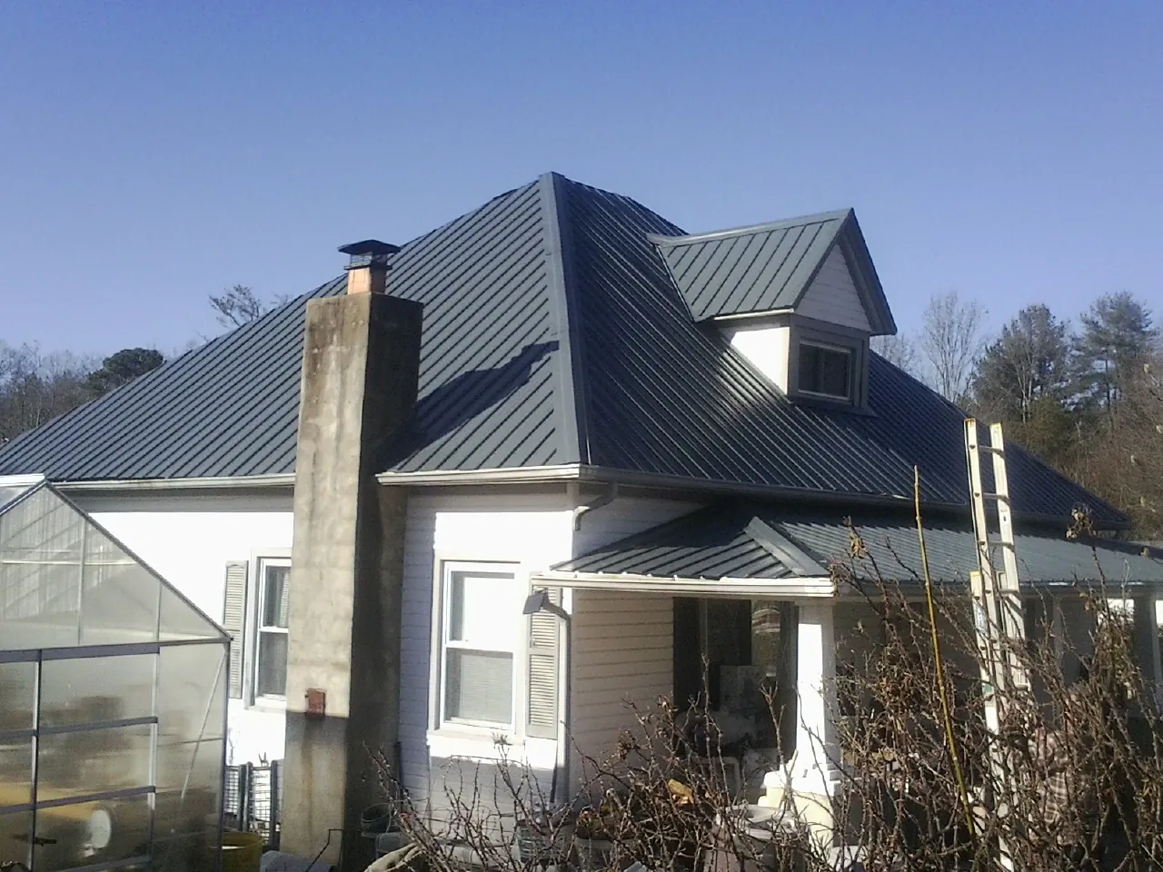Dark blue standing seam metal roof on a white farmhouse with dormer — Slate & Tile Roof Repair by Roofing Brothers in East Palestine