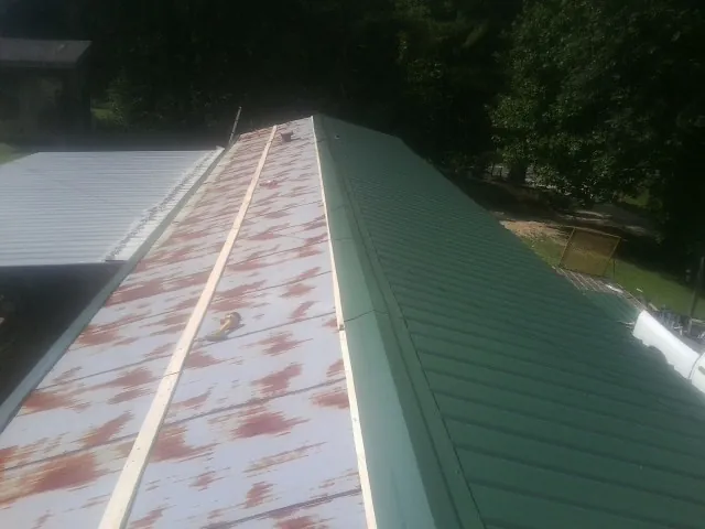 Old rusted panels beside newly installed green metal roofing — Wind Damage Roof Repair by Roofing Brothers in East Palestine