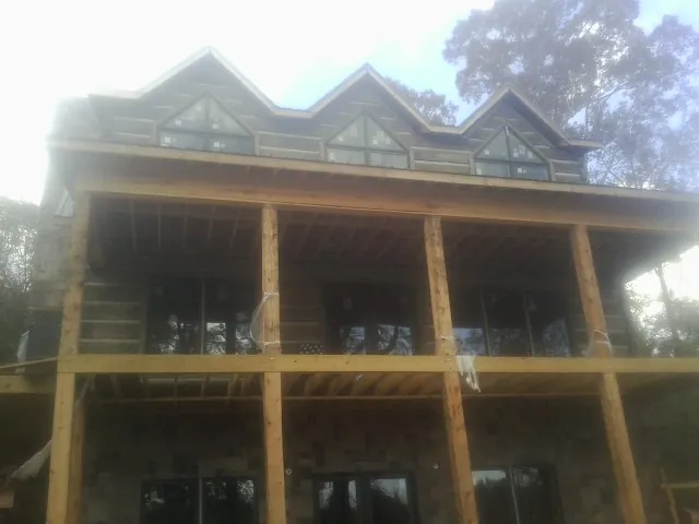 Dormers and porch framing on a large log home under construction — Roof Coating work by our crew in East Palestine