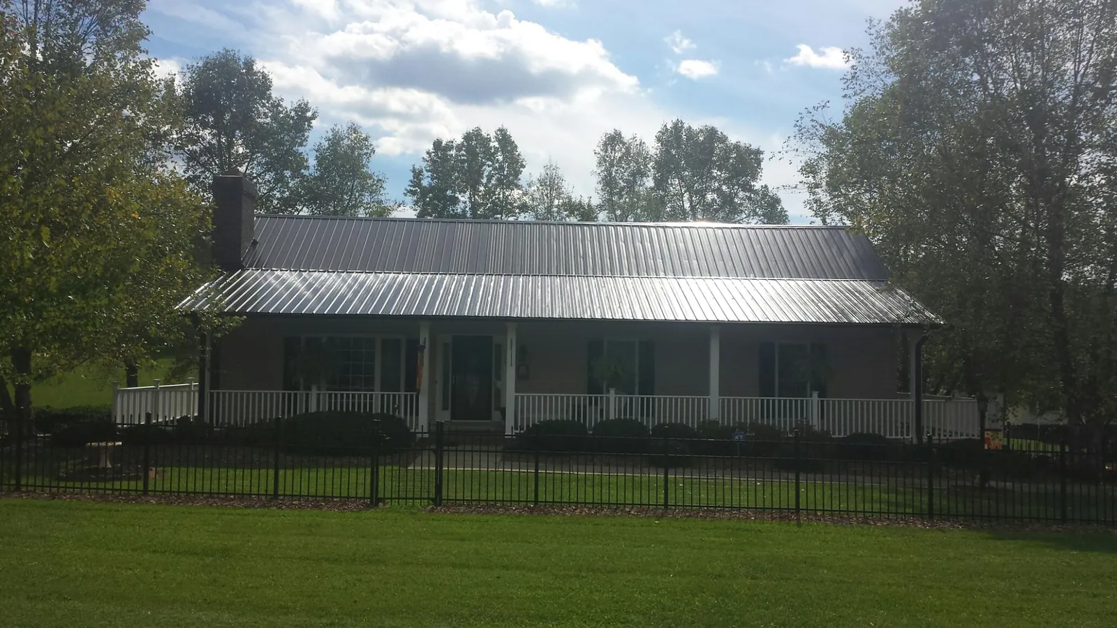 Gray metal roof on a brick ranch with a full width front porch — Gutter Guard Installation work by our crew in East Palestine
