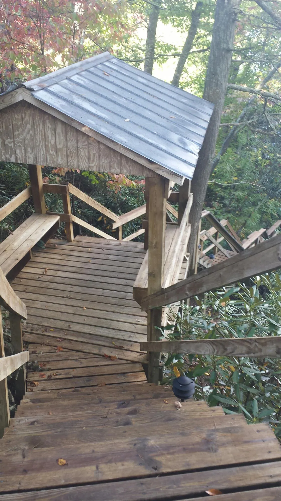 Metal roofed shelter over wooden steps on a wooded walkway — Skylight Repair & Installation work by our crew in East Palestine