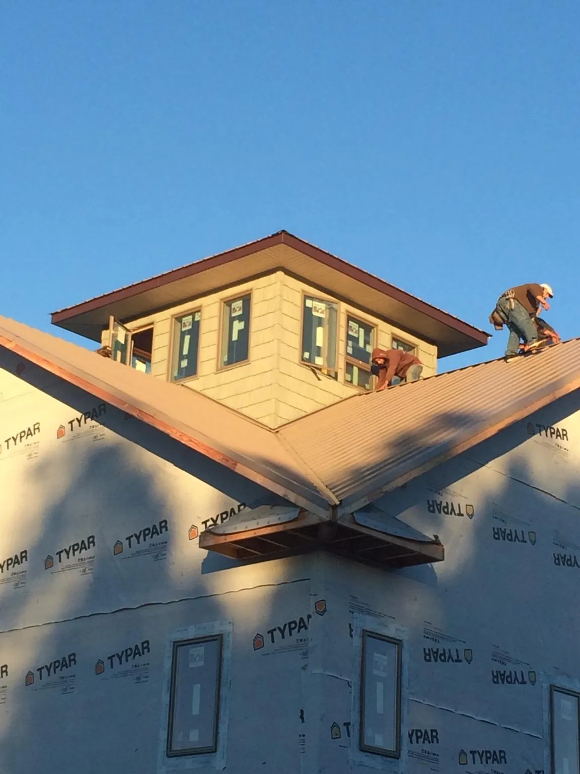 Roofers working around a rooftop cupola on a new metal roof at sunset — Roof Waterproofing in East Palestine by Roofing Brothers